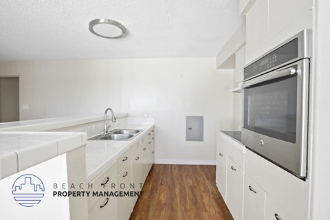 A kitchen with white appliances and wooden floors.