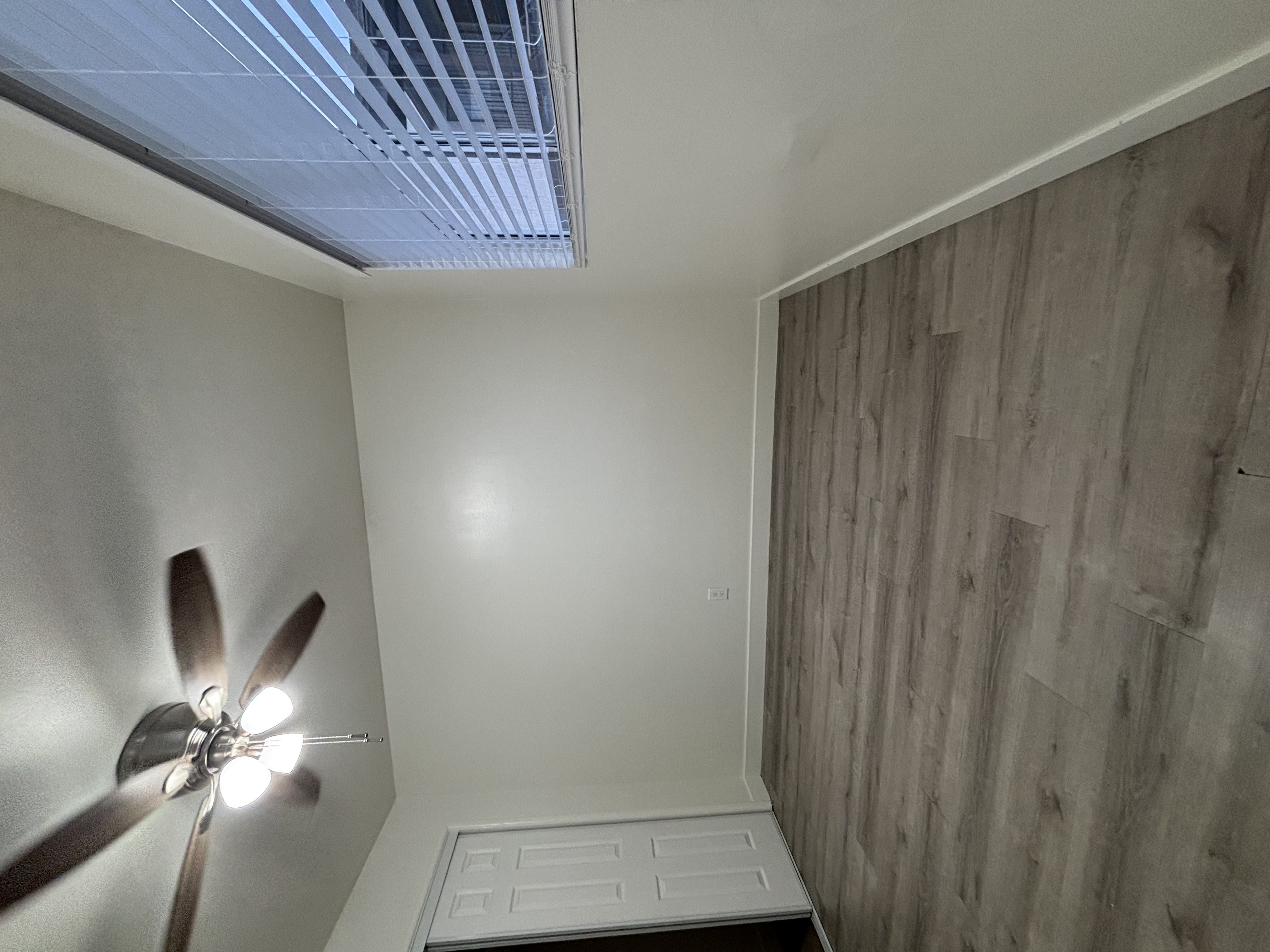 A room with a ceiling fan and a wooden wall.