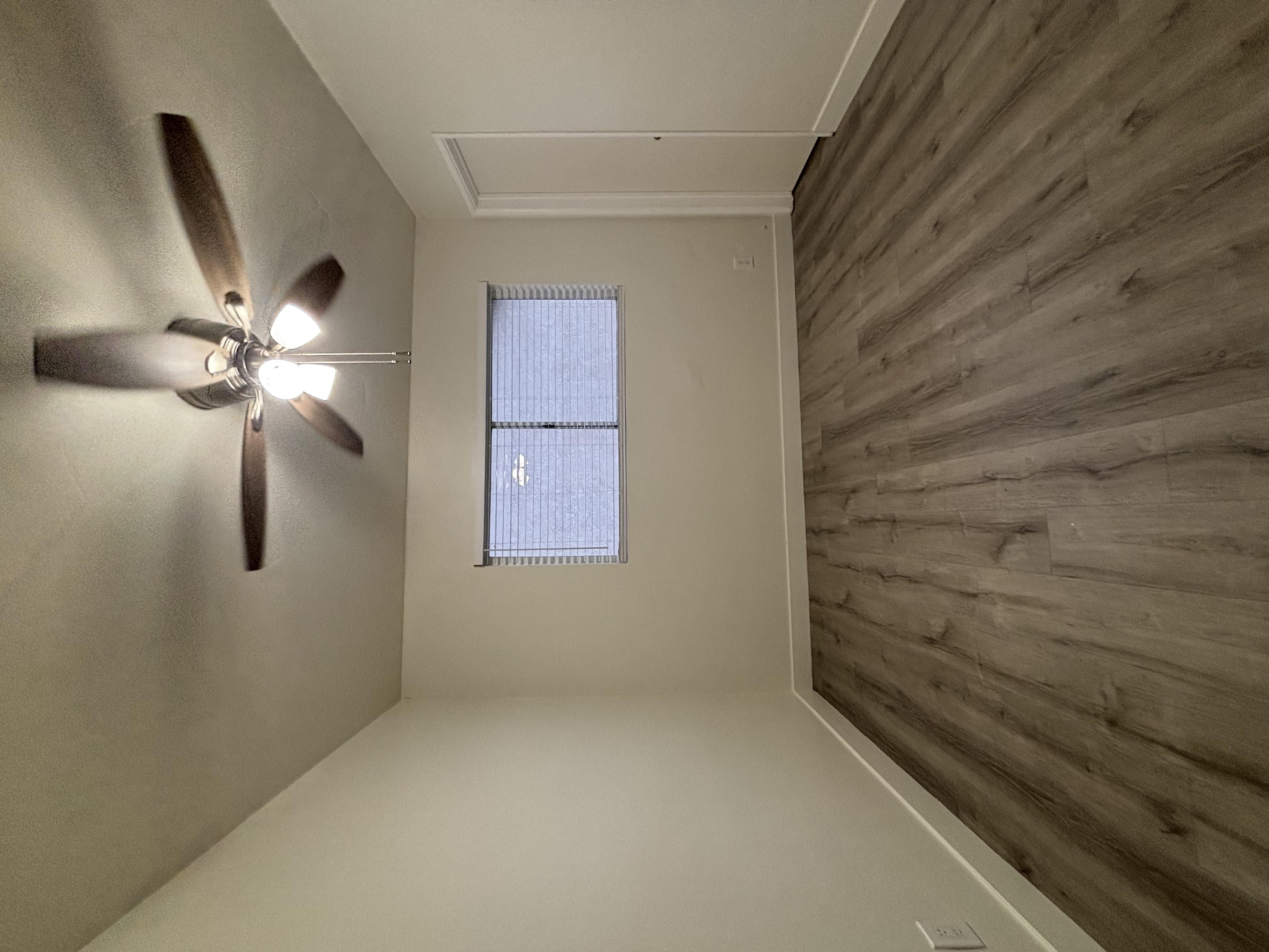 A room with a ceiling fan and a window.