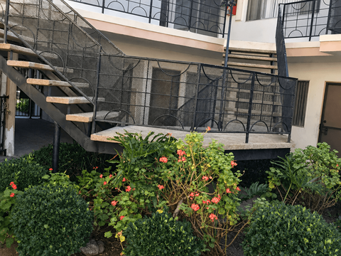 A staircase with a black railing and a building in the background.