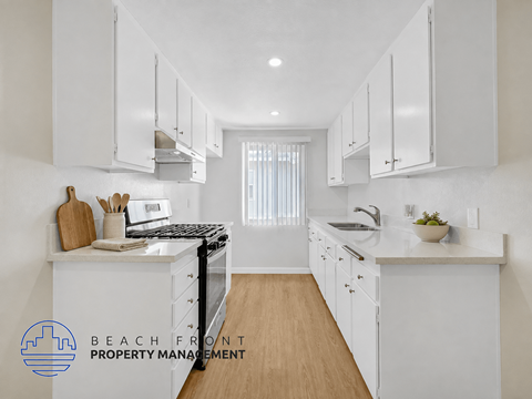 A kitchen with white cabinets and a wooden floor.
