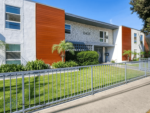 A modern building with a grey and orange facade and a metal fence in front.