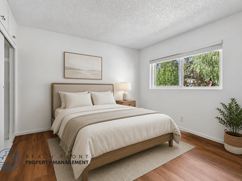 A bedroom with a large bed and a window overlooking a green area.