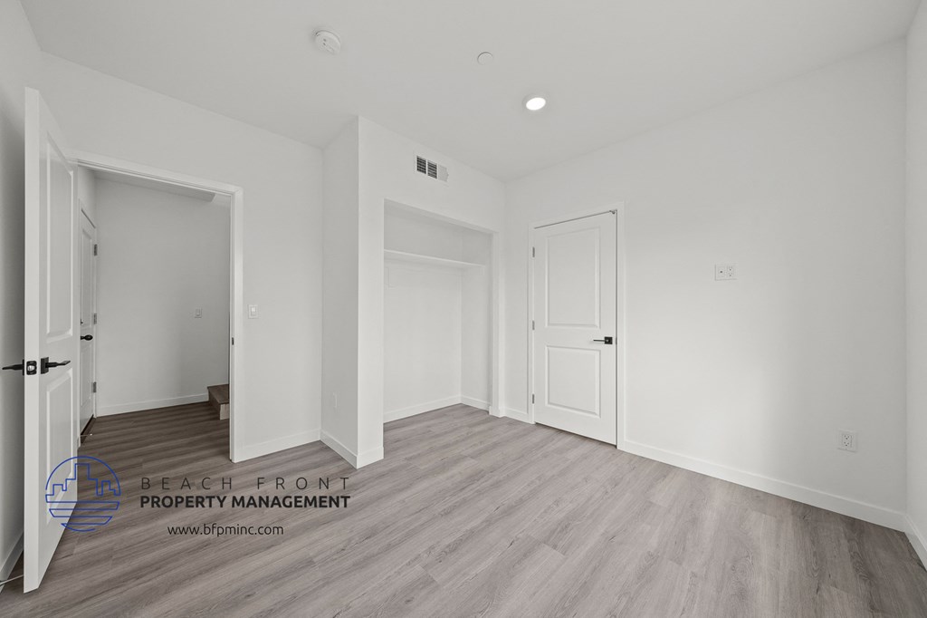 a bedroom with white walls and wood flooring and white doors