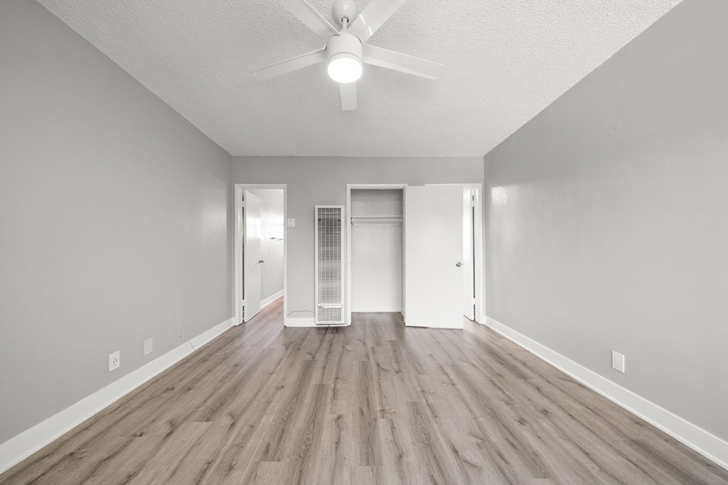 the spacious living room with hardwood flooring and a ceiling fan