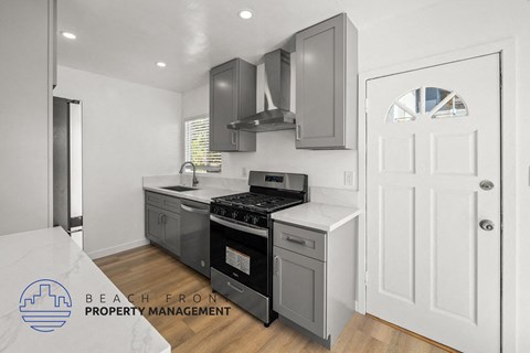 A modern kitchen with a stove top oven and a white door.