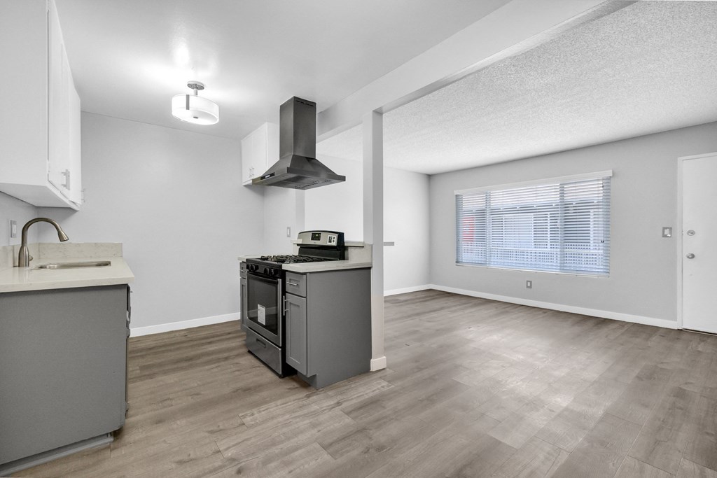 an empty kitchen and living room with a stove and a window