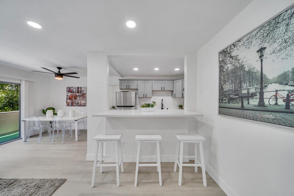 an open kitchen and dining area with a large window and a kitchen island with bar