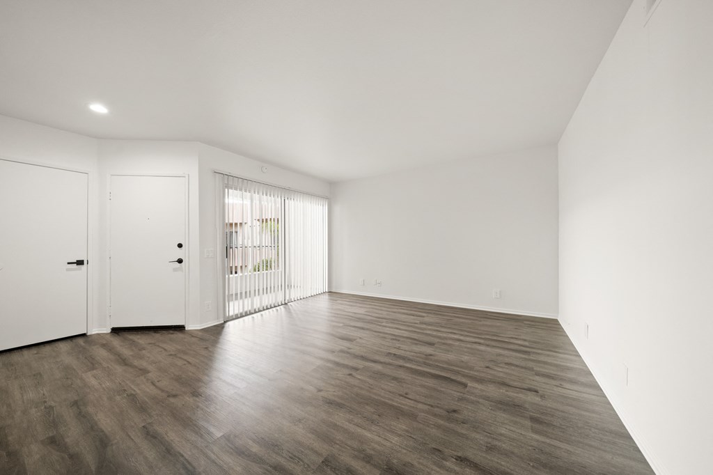 an empty living room with white walls and wood flooring