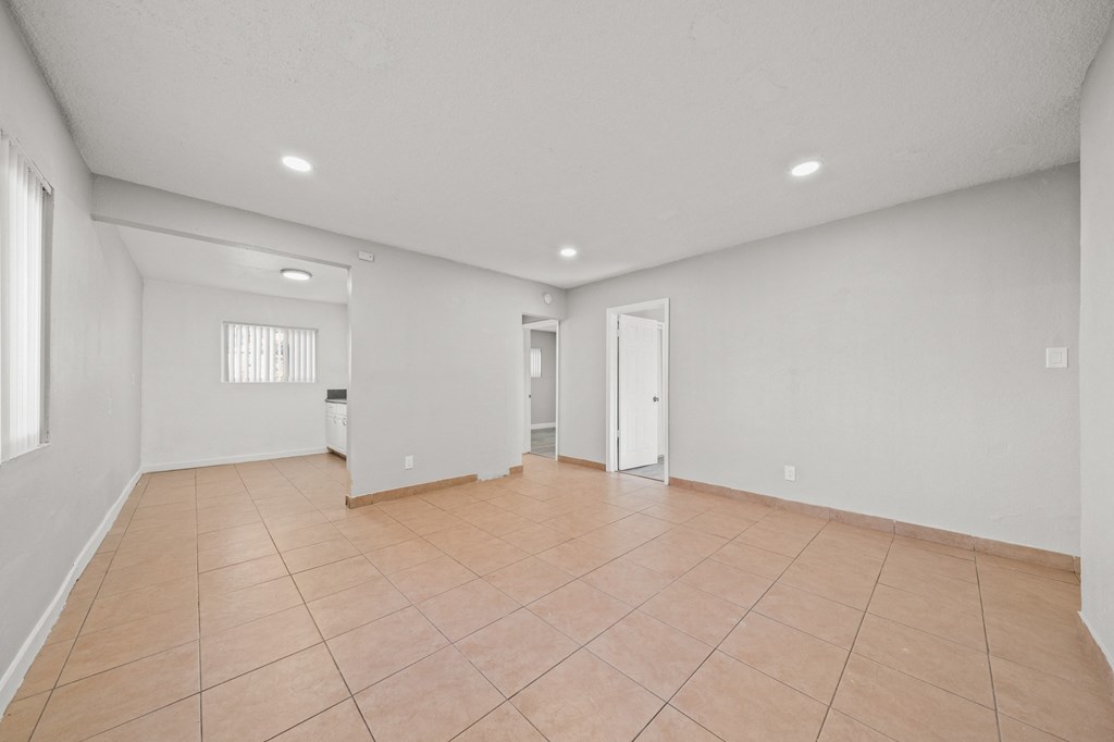 the spacious living room with tiled floors and white walls