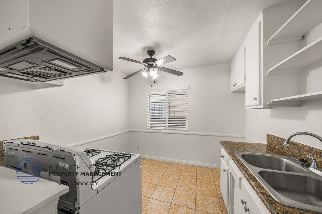 an empty kitchen with a stove and a ceiling fan