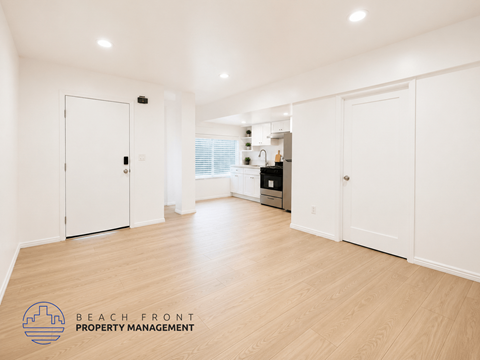 A spacious room with white doors and wooden flooring.