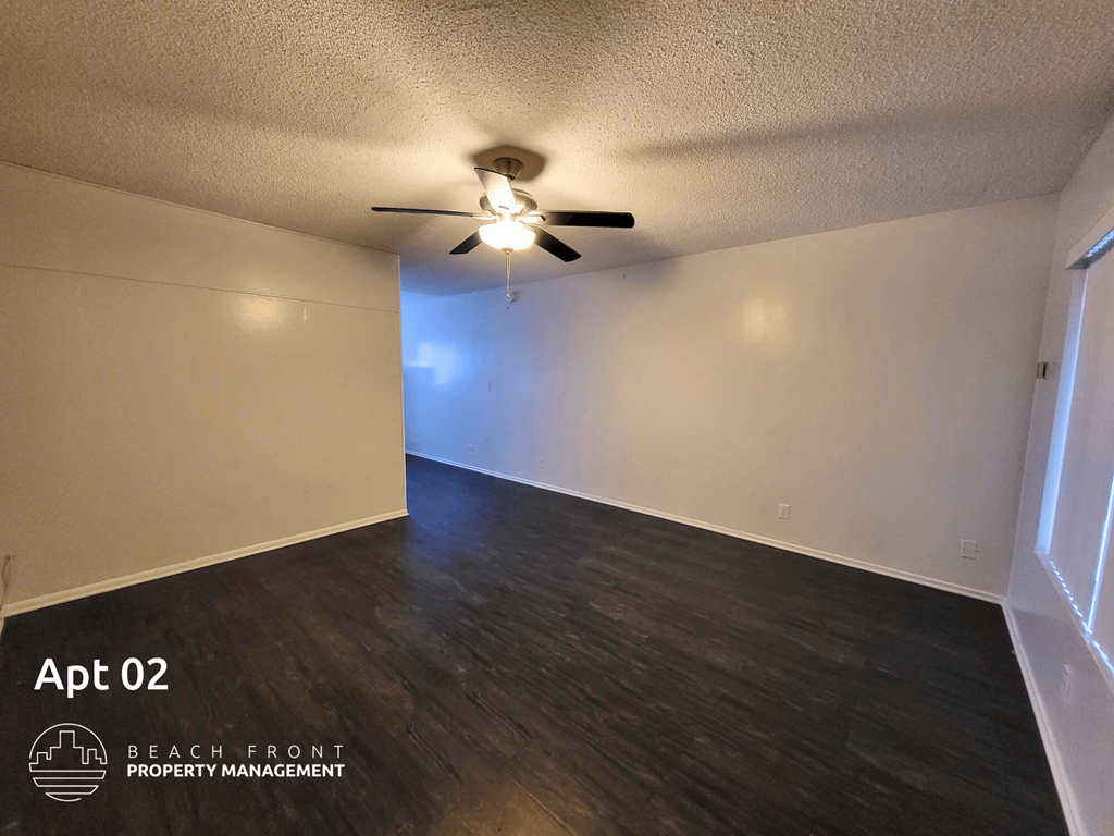 an empty living room with a ceiling fan and wood floors
