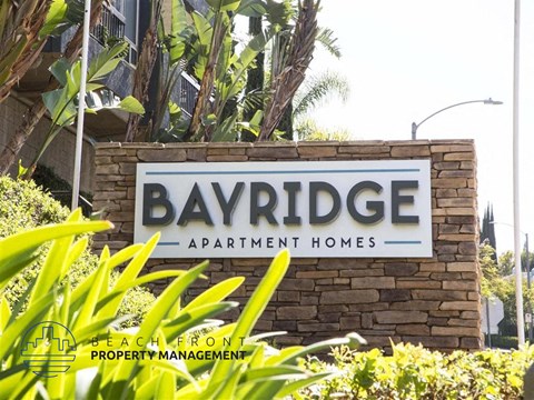 A sign for Bayridge Apartment Homes is displayed in front of some greenery.