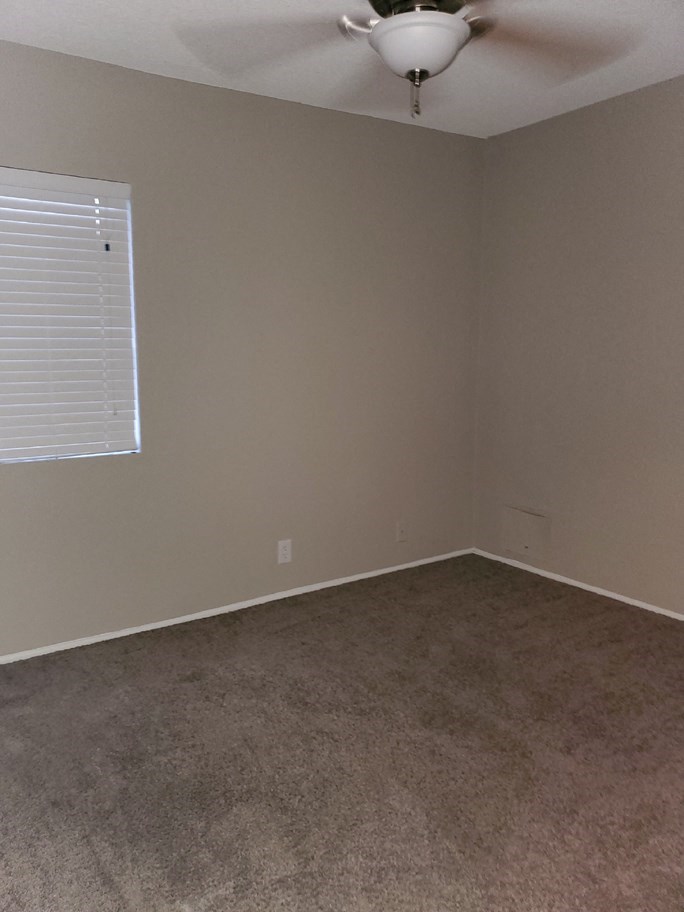 an empty room with a ceiling fan and a window