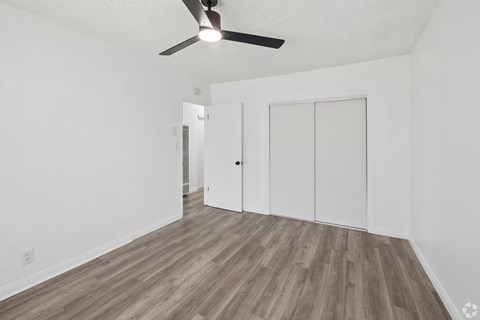 A room with a ceiling fan and wood flooring.