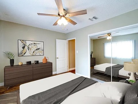 A bedroom with a bed, dresser, and ceiling fan.