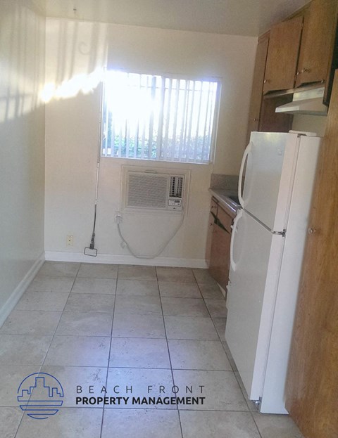 an empty kitchen with a refrigerator and a window