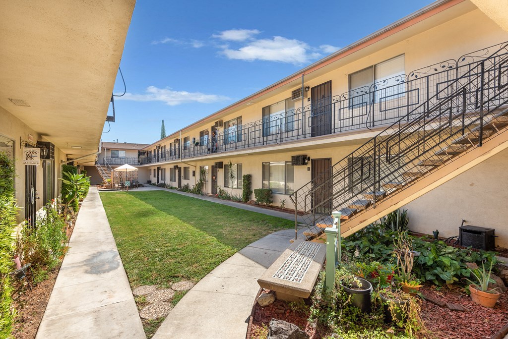 a courtyard with a lawn and a building with balconies
