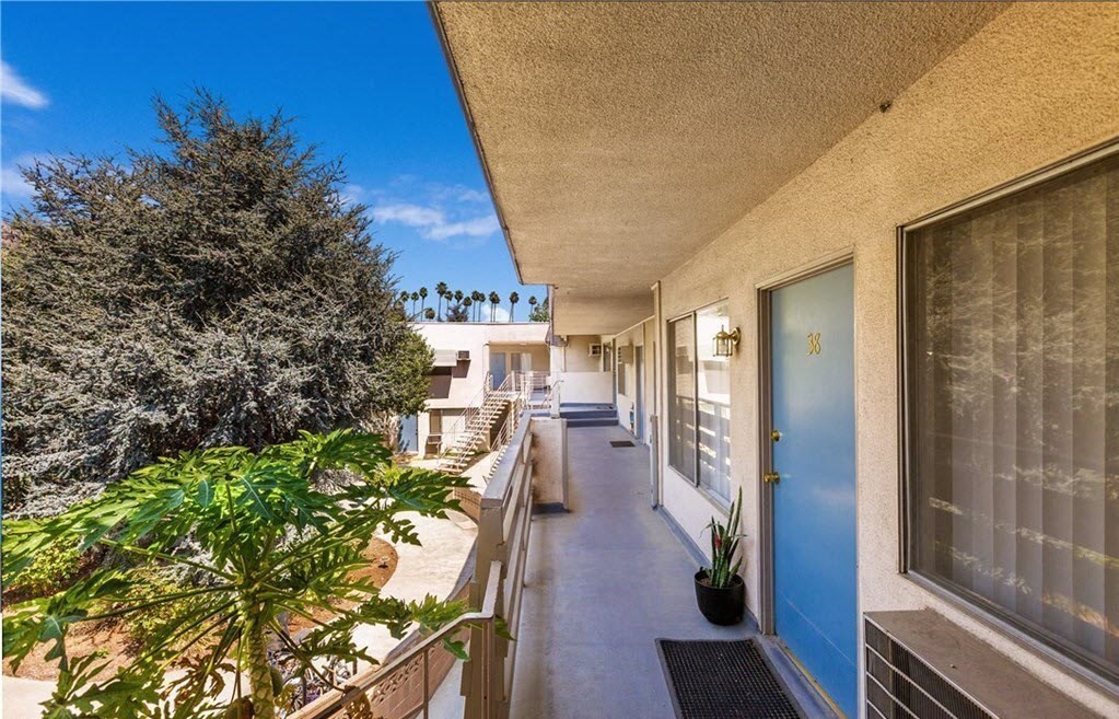 a balcony with a blue door and some plants and trees