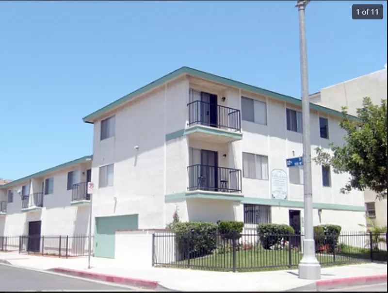 A white building with a green roof and a sign on the front.