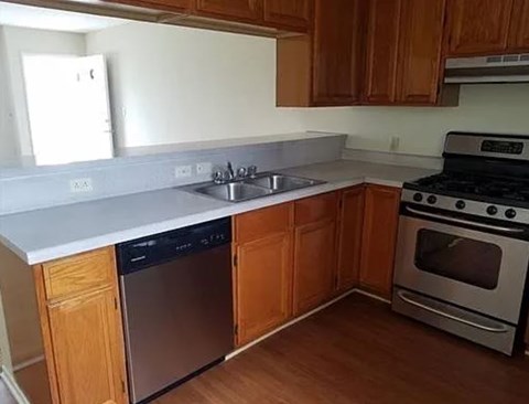 A kitchen with wooden cabinets and a stainless steel dishwasher.