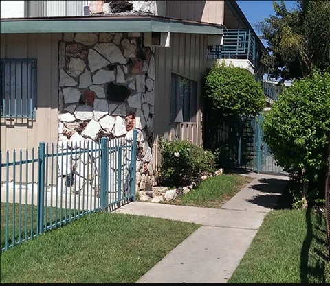 a house with a blue fence and a bicycle in the yard