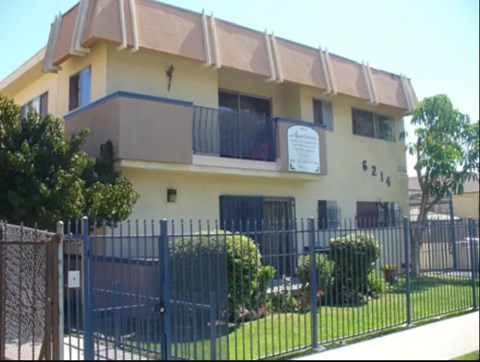 A building with a sign on the balcony and a fence in front.