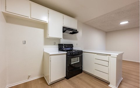 A kitchen with a black stove top oven and white cabinets.