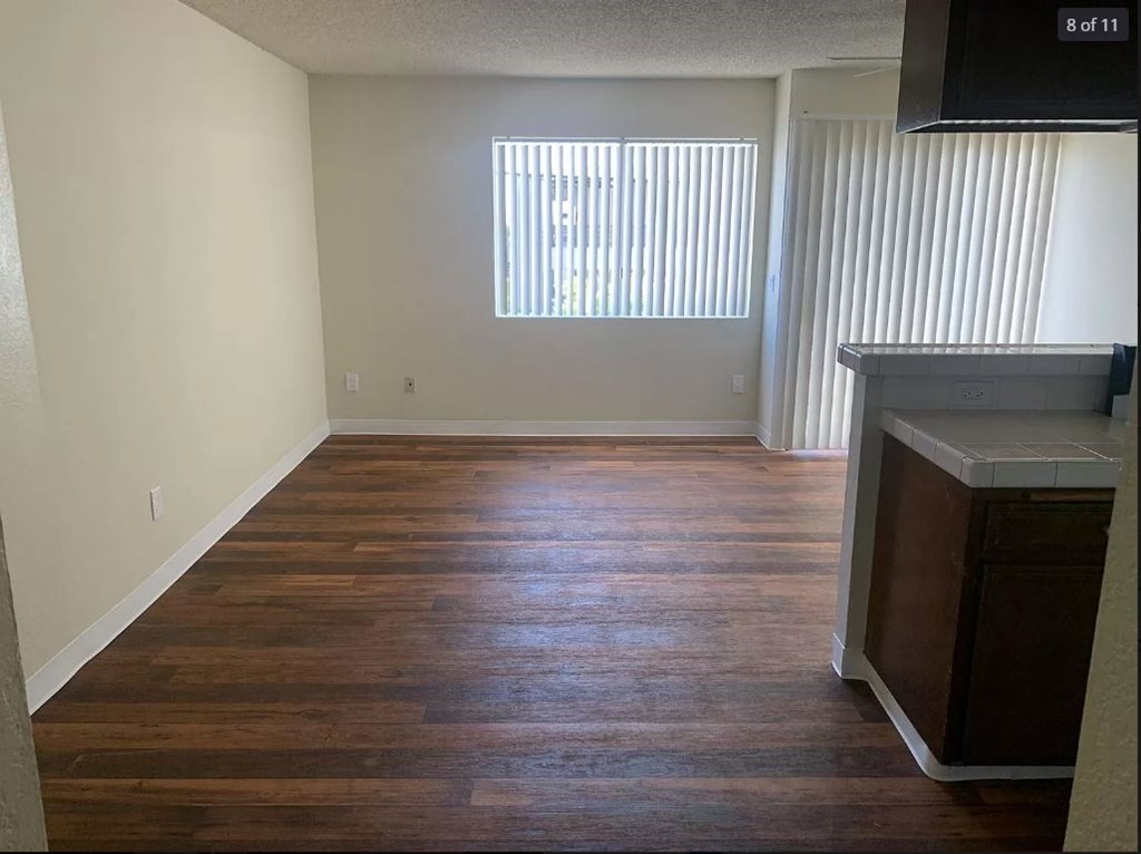 A room with wooden floors and a window with blinds.