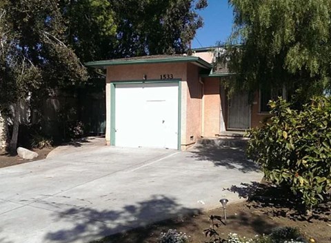 A garage with the number 1533 on it is surrounded by trees and bushes.