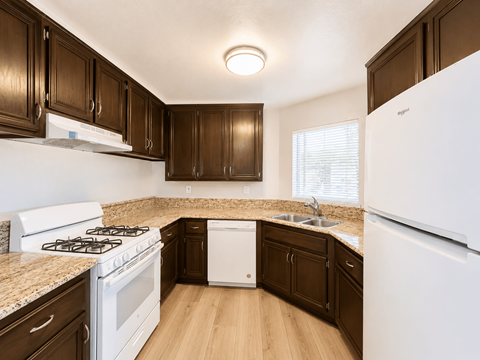 A kitchen with white appliances and brown cabinets.