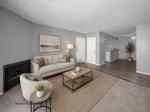 A living room with a white couch, a chair, a coffee table, and a painting on the wall.