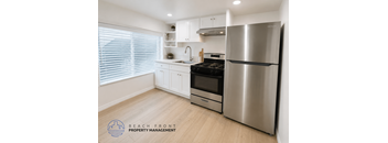 A modern kitchen with a stainless steel refrigerator and wooden flooring.