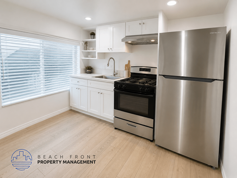 A modern kitchen with a stainless steel refrigerator and wooden flooring.
