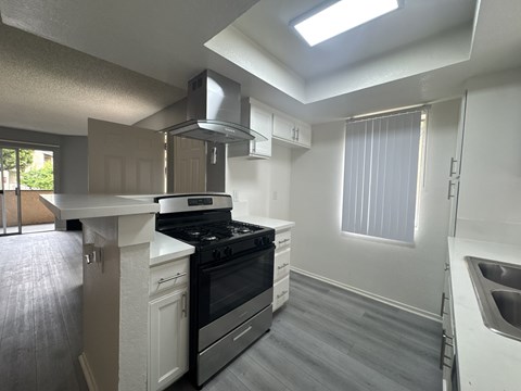 A kitchen with a stove, sink, and cabinets.