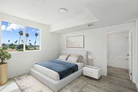 A bedroom with a large bed and a view of palm trees outside the window.