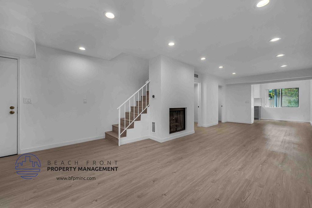 a large living room with hardwood floors and white walls