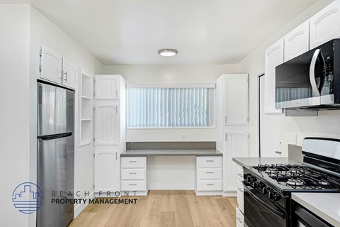 A kitchen with white cabinets and a stove top oven.