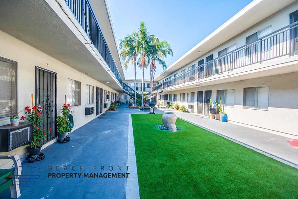 a courtyard of a building with green grass and palm trees