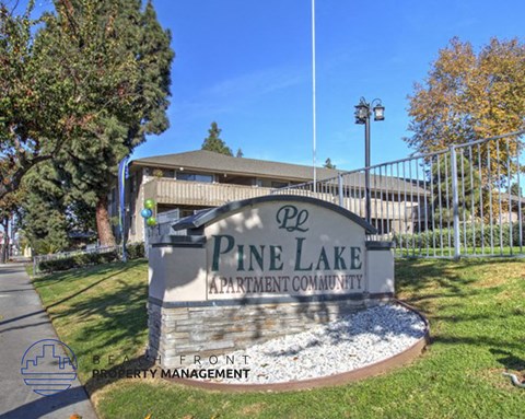 A sign for Pine Lake Apartment Community is displayed in front of a building.