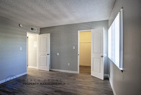 A room with a white door and a window on the right side.