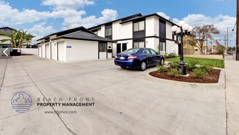 A car is parked in front of a building with the sign "Beach Front Property Management" on the ground.