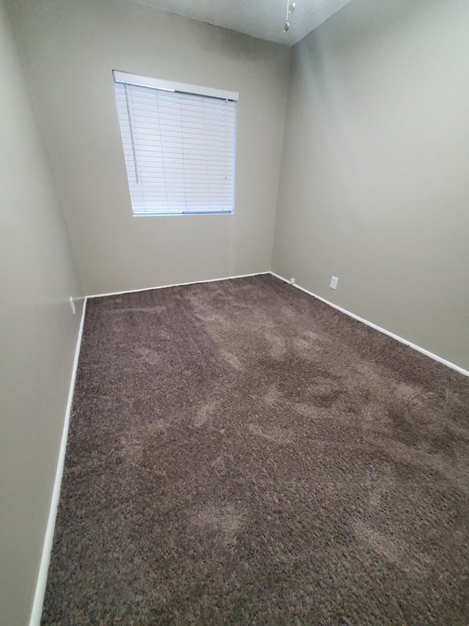 a empty room with carpet and a window