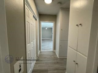 a long hallway with white cabinets and a door to a bathroom