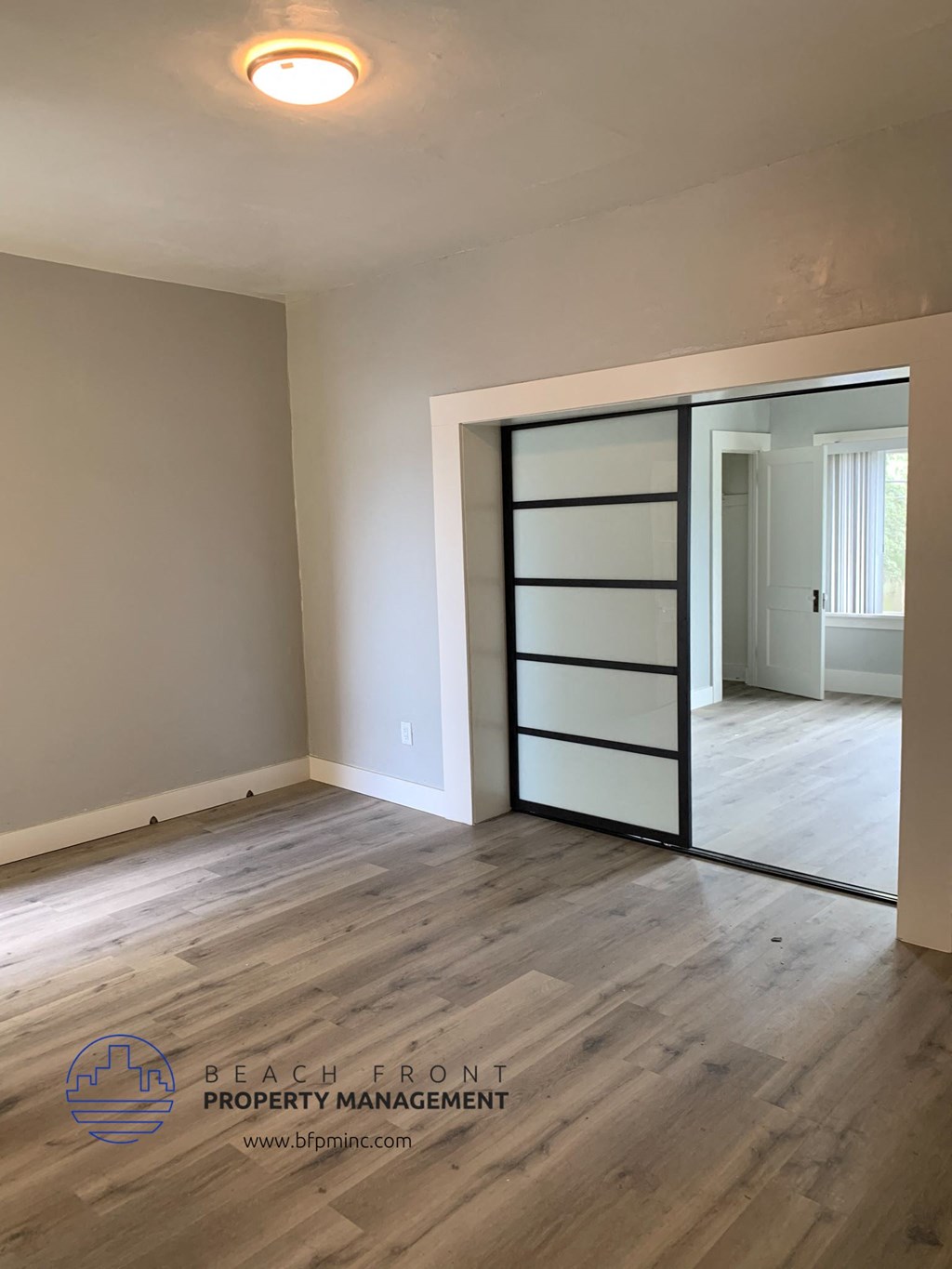 an empty living room with a sliding glass door and hardwood floor