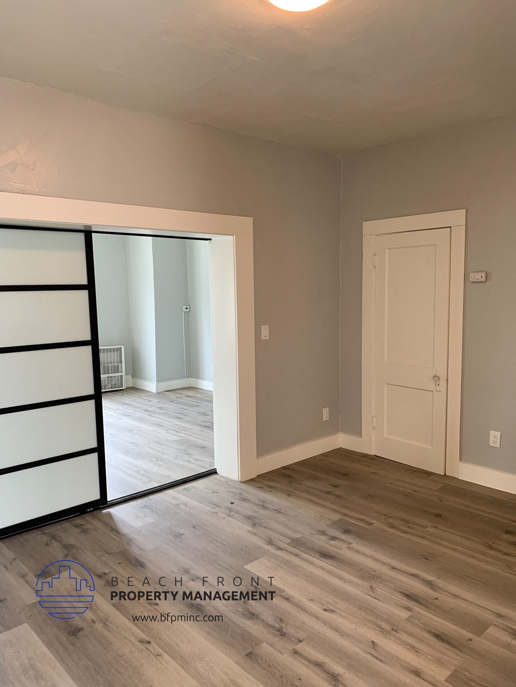 a bedroom with a mirrored closet and a door to a living room