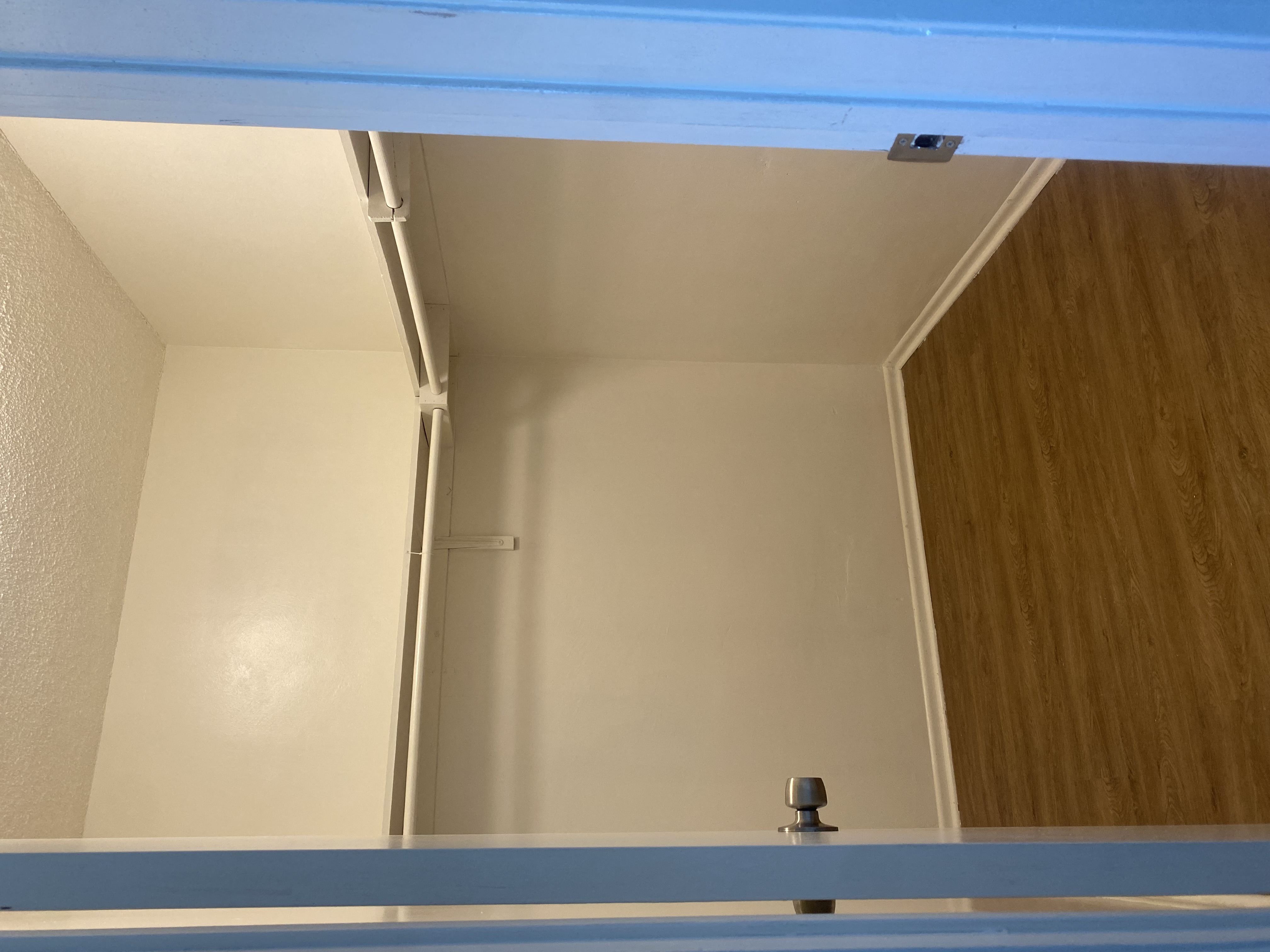 a small closet with white walls and a wooden floor