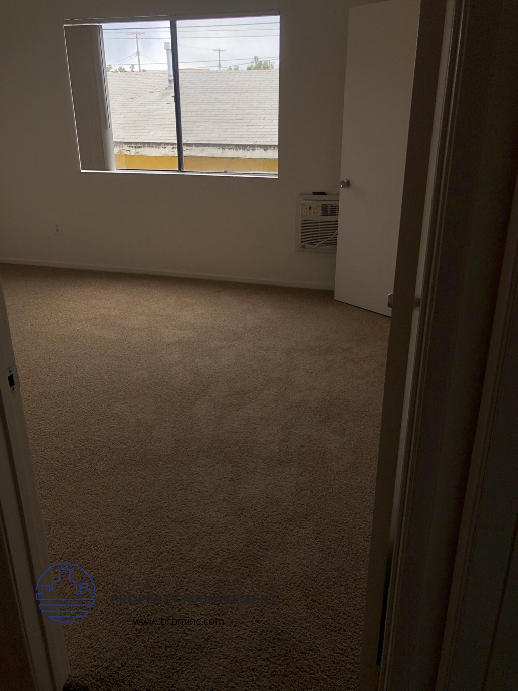 a room with a window and a carpeted floor
