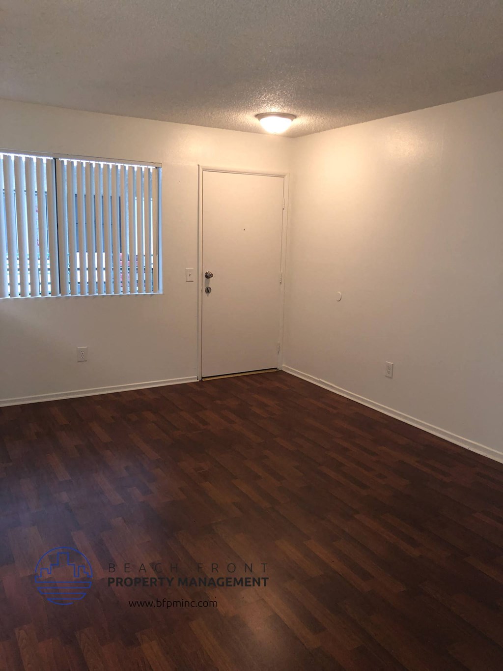 the interior of an empty living room with wooden floors and a window
